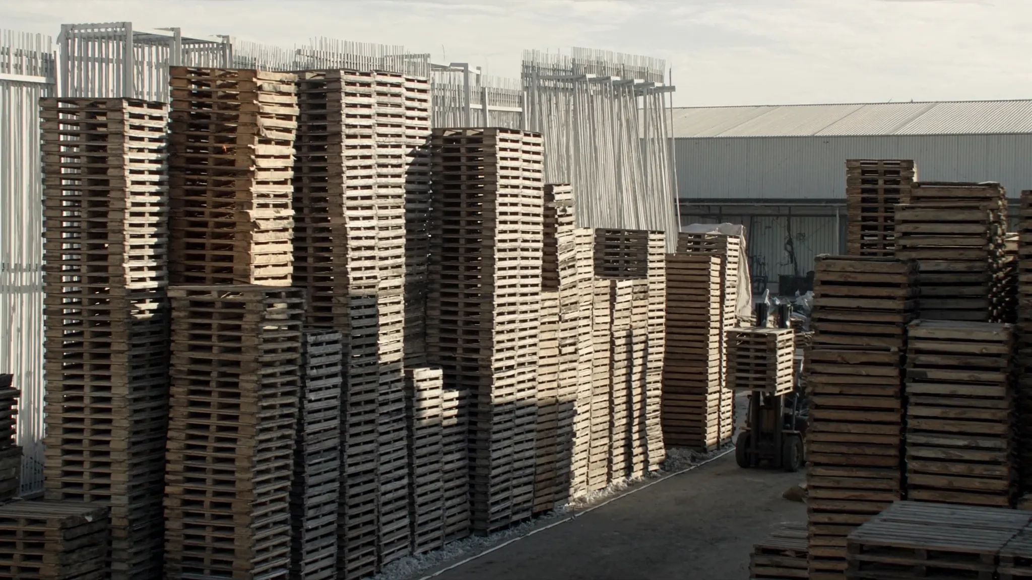 Estibas de tarimas de madera usadas en patio industrial listas para recolección